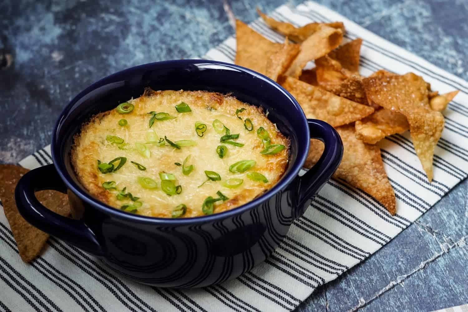 crab rangoon dip in a blue bowl with fried wonton chips