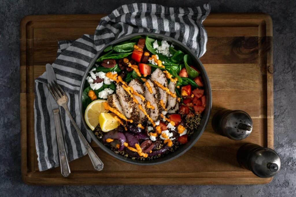 Chicken Quinoa and romesco bowl with a striped napkin