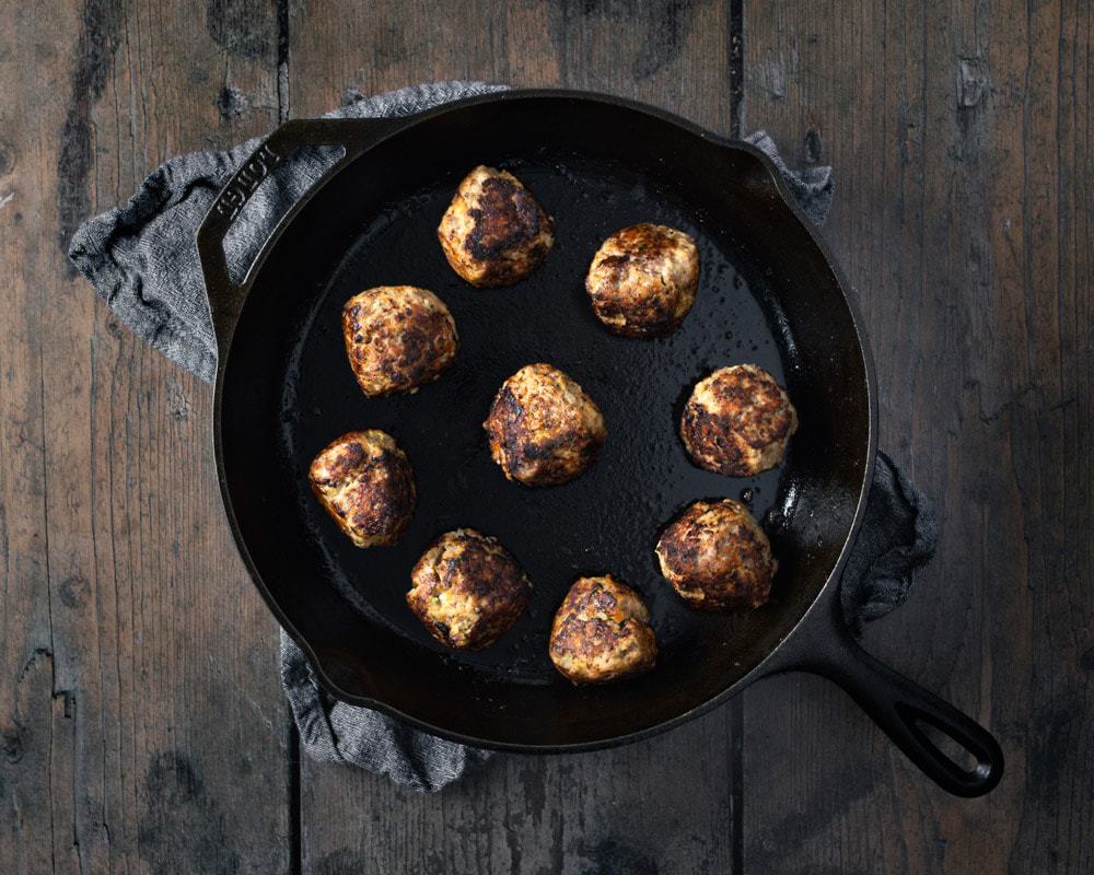 searing meatballs in a cast iron
