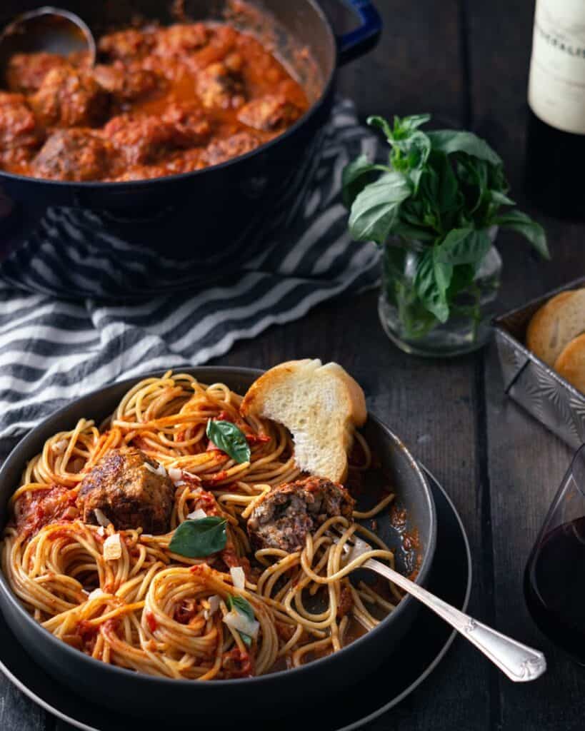 bowl of meatballs and spaghetti and a pot full of marinara