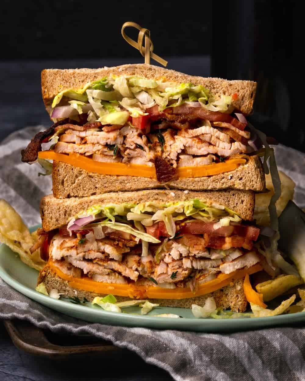 Up close cajun turkey breast sandwich with lettuce, bacon, tomatoes, and cheese. 
