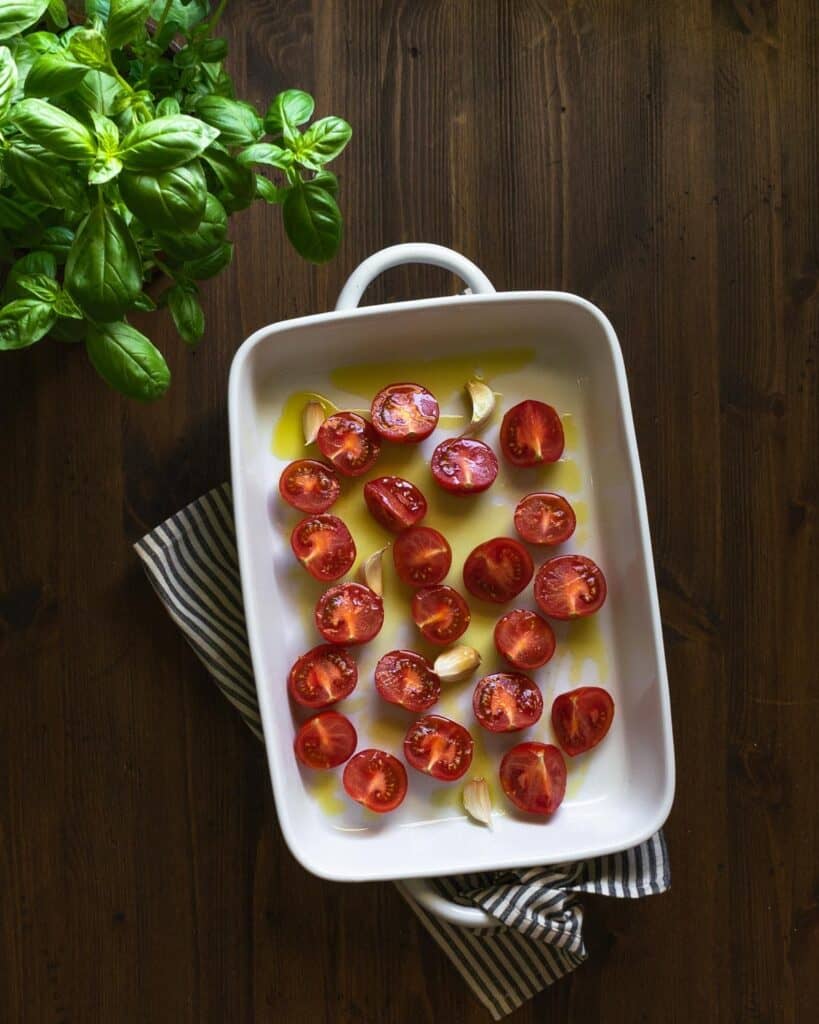 fresh tomatoes and garlic in a baking dish before roasting