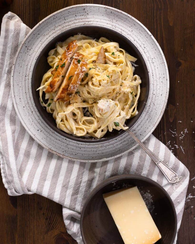a bowl of pasta and roasted garlic alfredo sauce and parmesan cheese