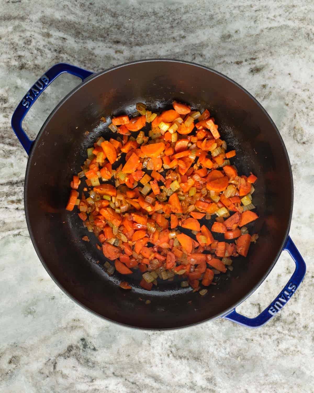 Caramelized tomato paste with sautéed vegetables in a large pot.