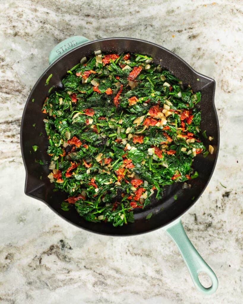 sautéed spinach and sun dried tomatoes in a skillet