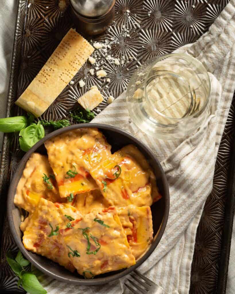 A bowl of lobster ravioli with cream sauce with parmesan cheese and wine.