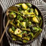 Roasted asparagus and brussels sprouts in a brown bowl.