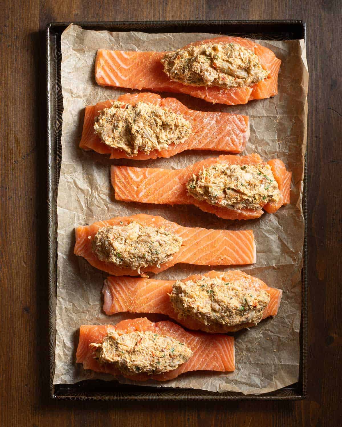 Salmon filets stuffed with crab meat on a parchment lined baking sheet prior to baking.