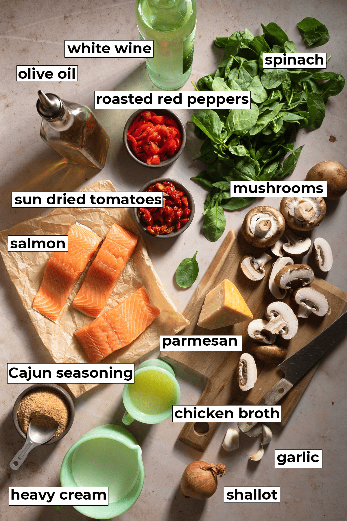 Ingredients for cajun salmon pasta including parmesan, mushrooms, spinach, roasted red peppers, and sun dried tomatoes.