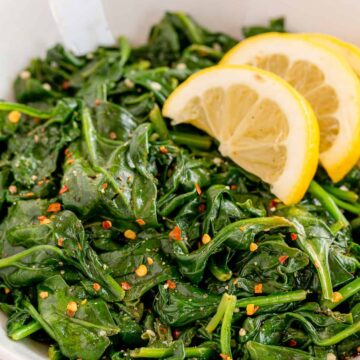 A bowl of sautéed spinach with lemon and red pepper flakes.