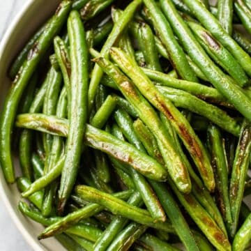 Up close bowl of roasted green beans with salt.