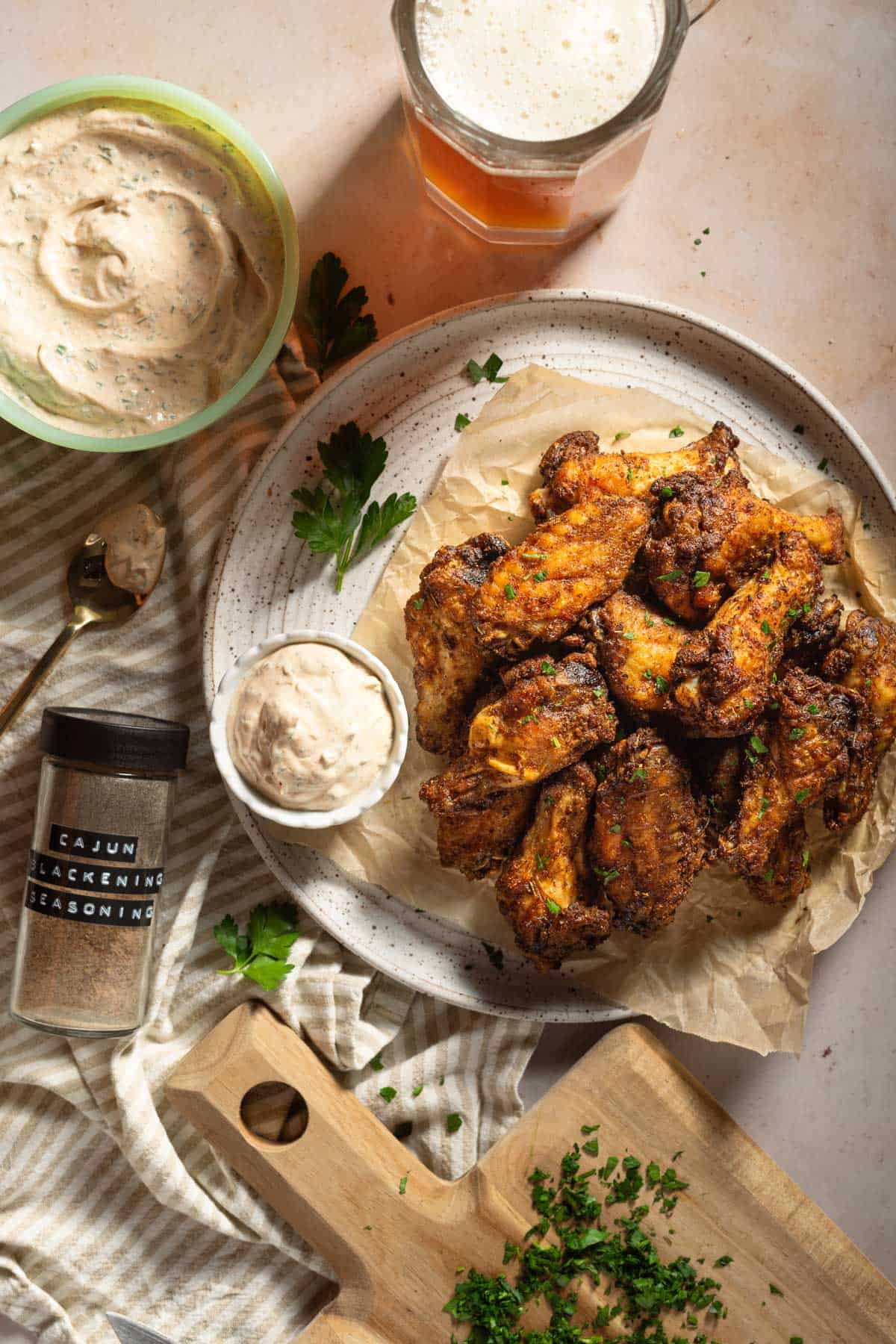 Blackened chicken wings on a plate with ranch, topped with parsley.