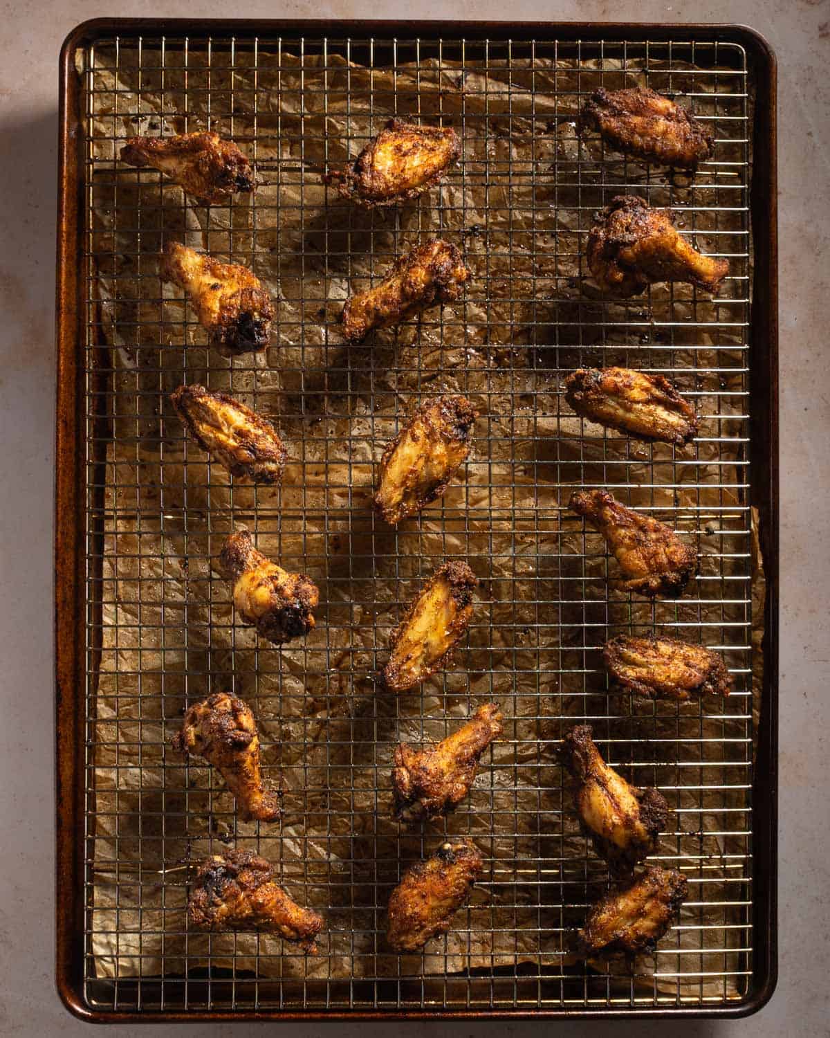 Baked chicken wings on a baking sheet and wire rack.