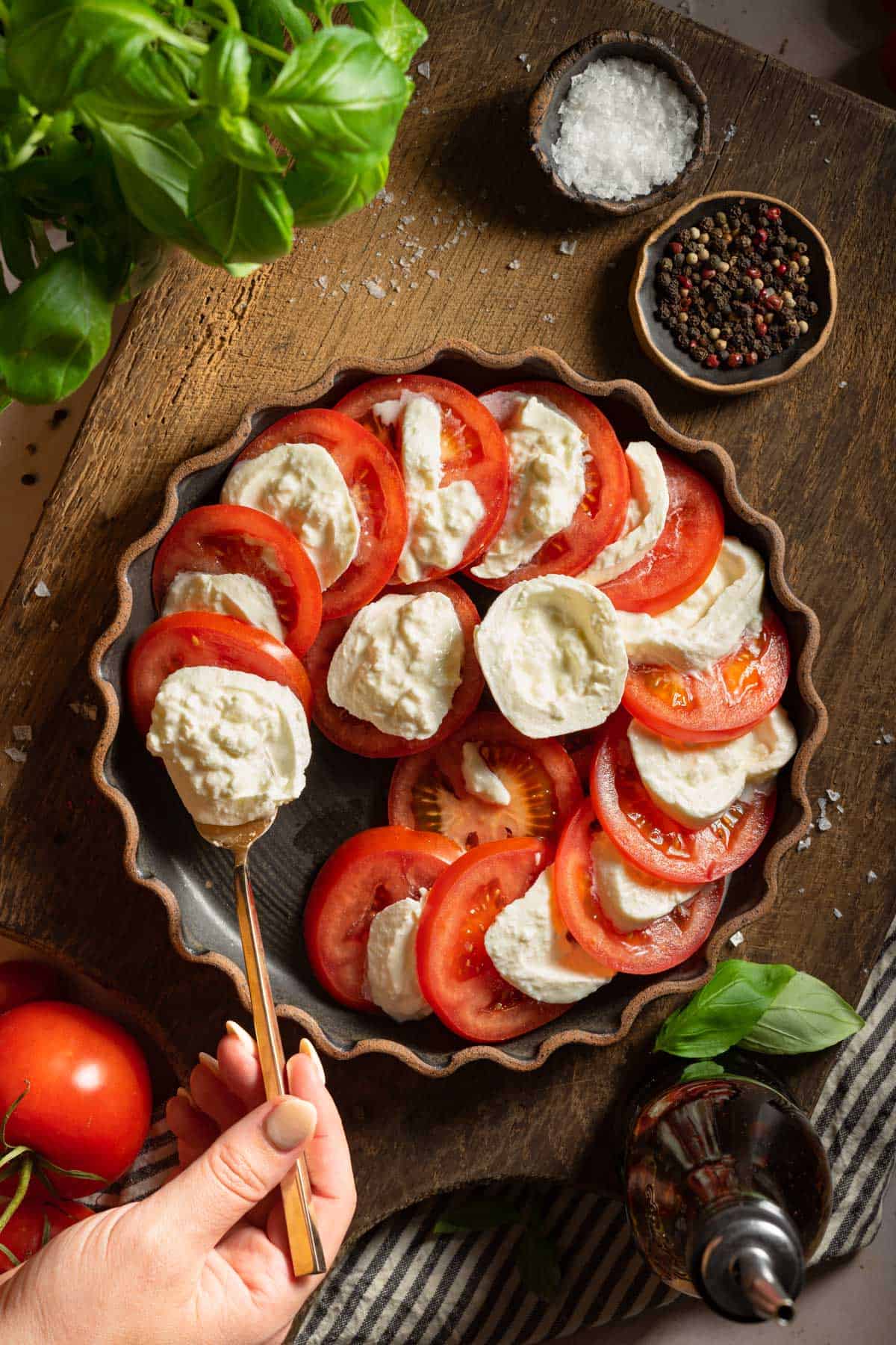 Adding burrata to a plate of tomatoes.