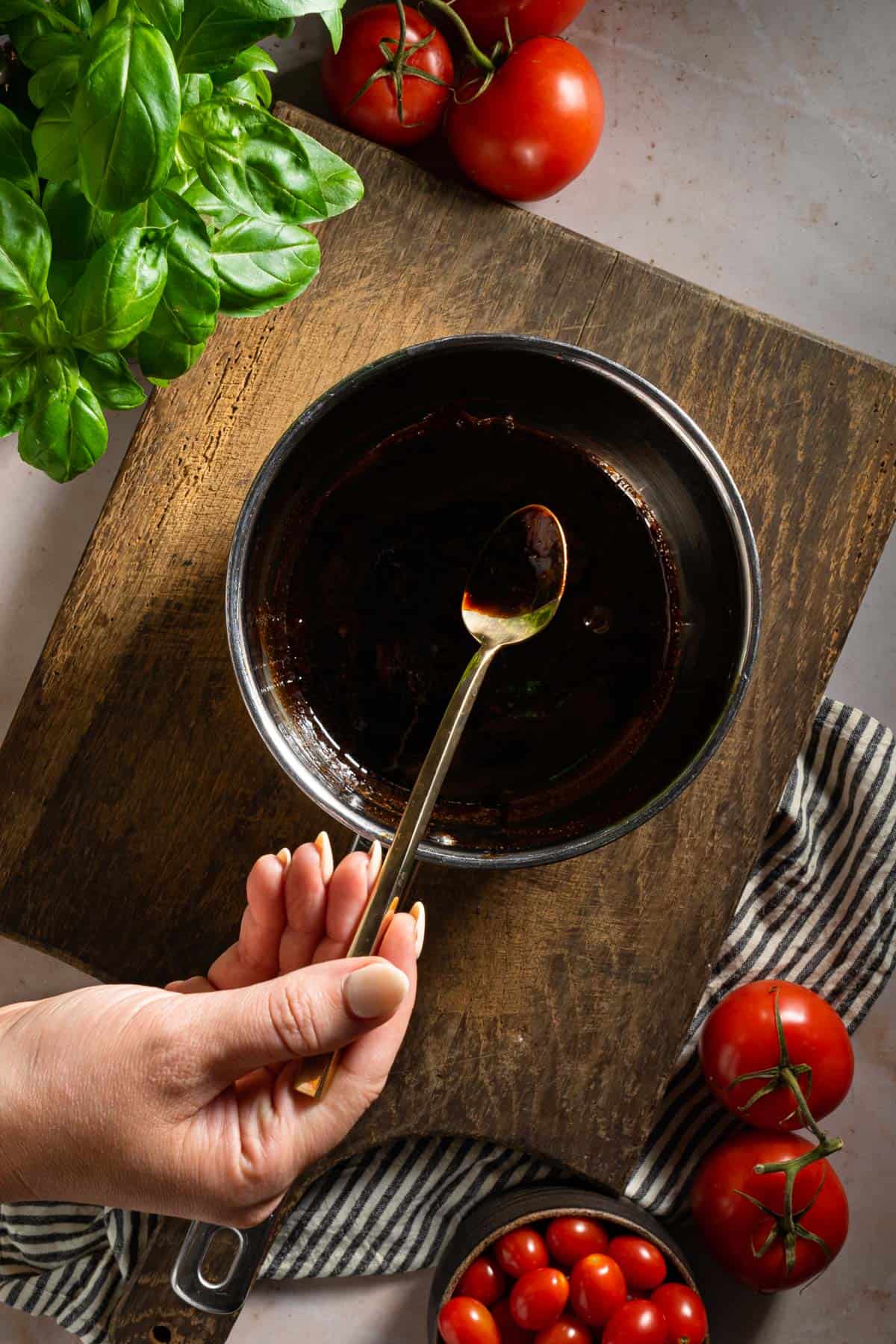 A spoon coated with balsamic glaze over a pot.