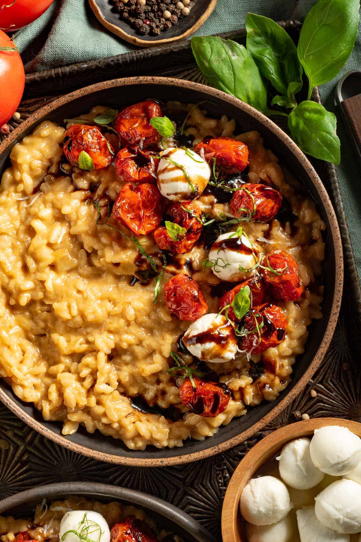 Up close view of caprese risotto in a bowl topped with basil and balsamic glaze.