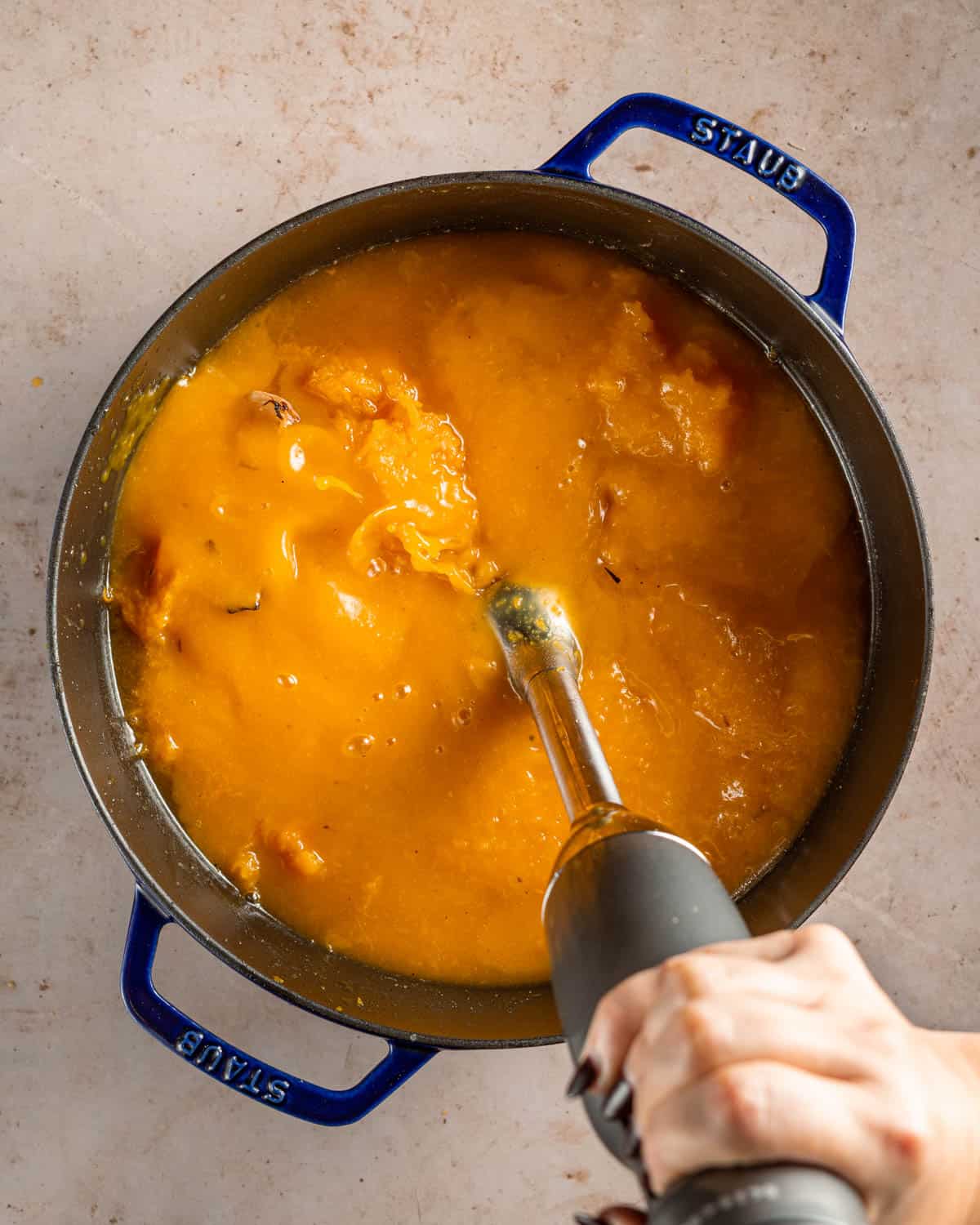 Pureeing butternut squash soup with an immersion blender.
