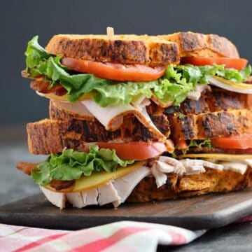 A Bacon Turkey Bravo Sandwich on a cutting board.