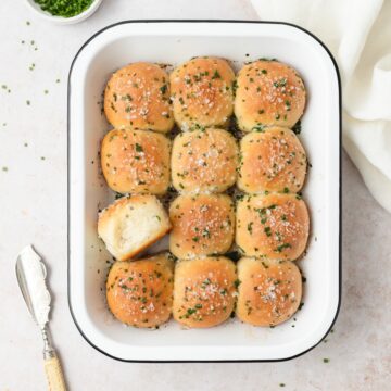 A pan of sourdough sour cream and chive pull-apart rolls topped with fresh chives.