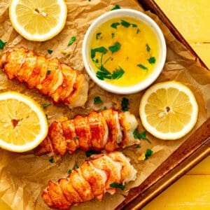 Butter Poached Lobster Tail on a baking tray with a side of butter and lemon.