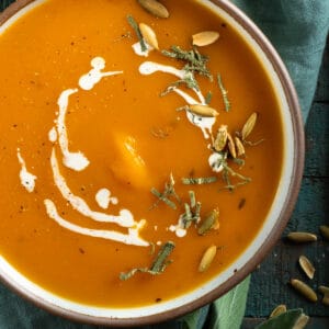A bowl of butternut squash soup with sage and nuts.