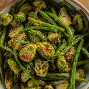 Roasted Green Beans and Brussel Sprouts in a bowl with fresh basil and lemon zest.