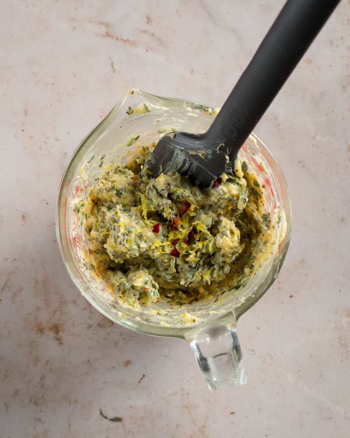 Garlic and herb compound butter in a glass measuring cup.