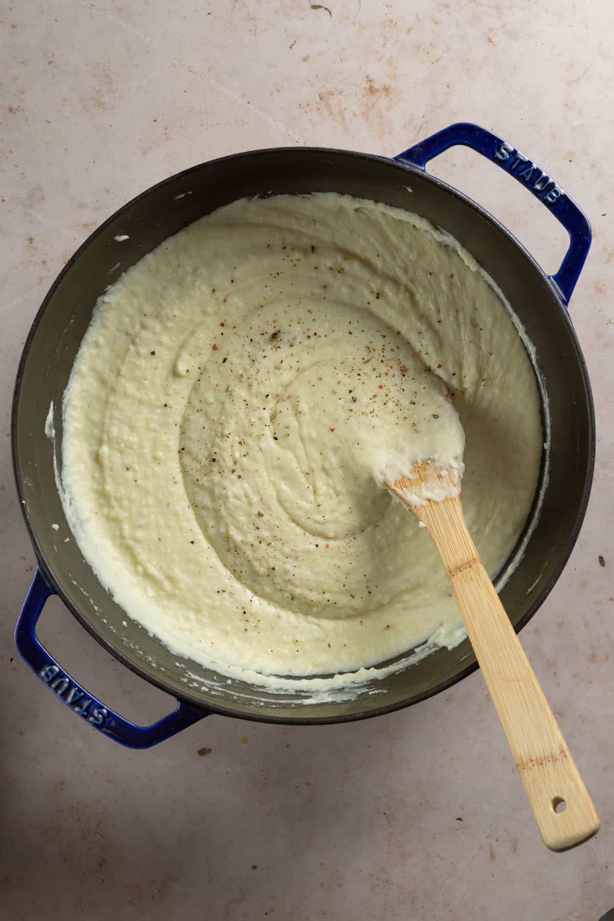 Creamy mashed potatoes in a pot with a wooden spoon.