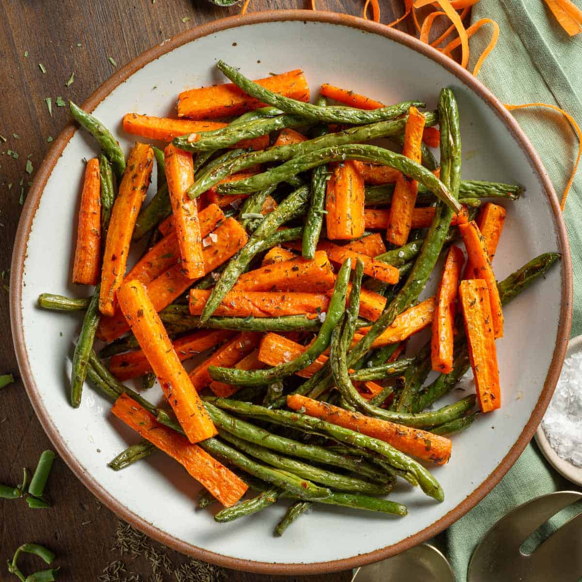Roasted carrots and green beans topped with spices in a serving bowl.