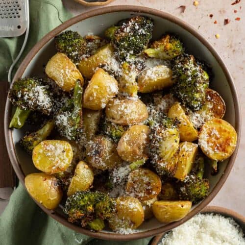 Roasted broccoli and potatoes topped with parmesan in a serving bowl.
