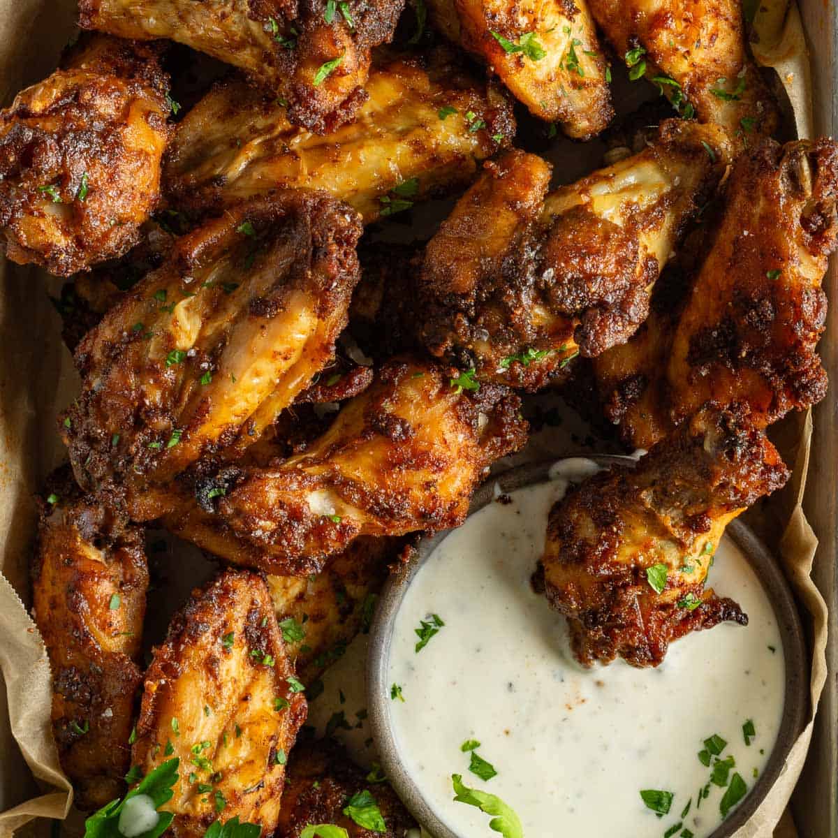 Up close dry rubbed chicken wings in ranch sauce.