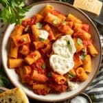 A bowl of rigatoni with arrabbiata sauce topped with fresh basil.