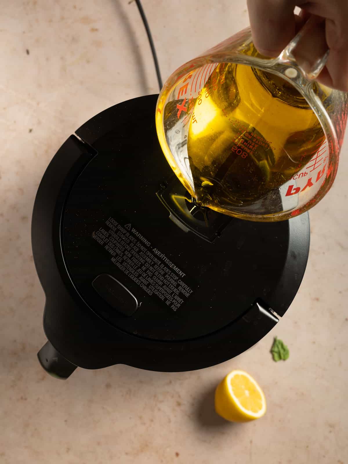 Drizzling olive oil into a food processor.