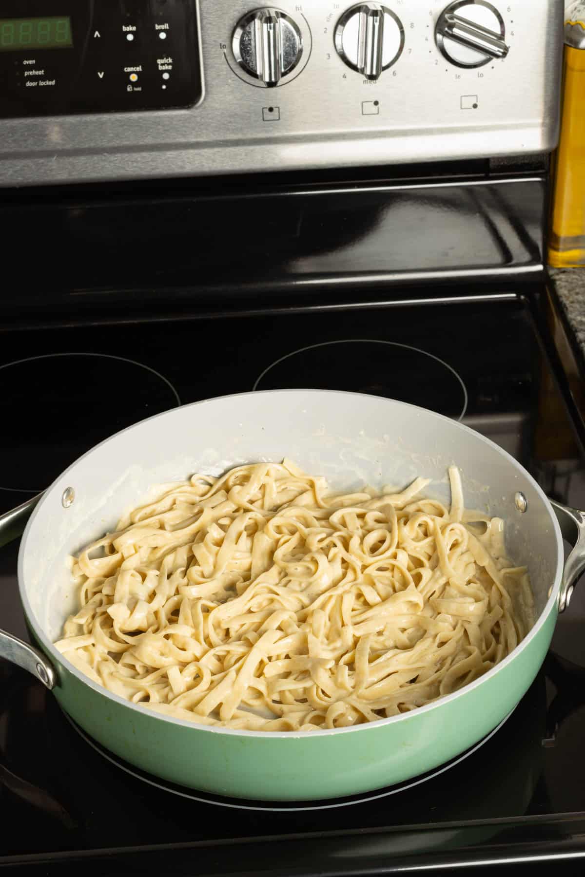 A pan full of fettuccine alfredo on the stove.