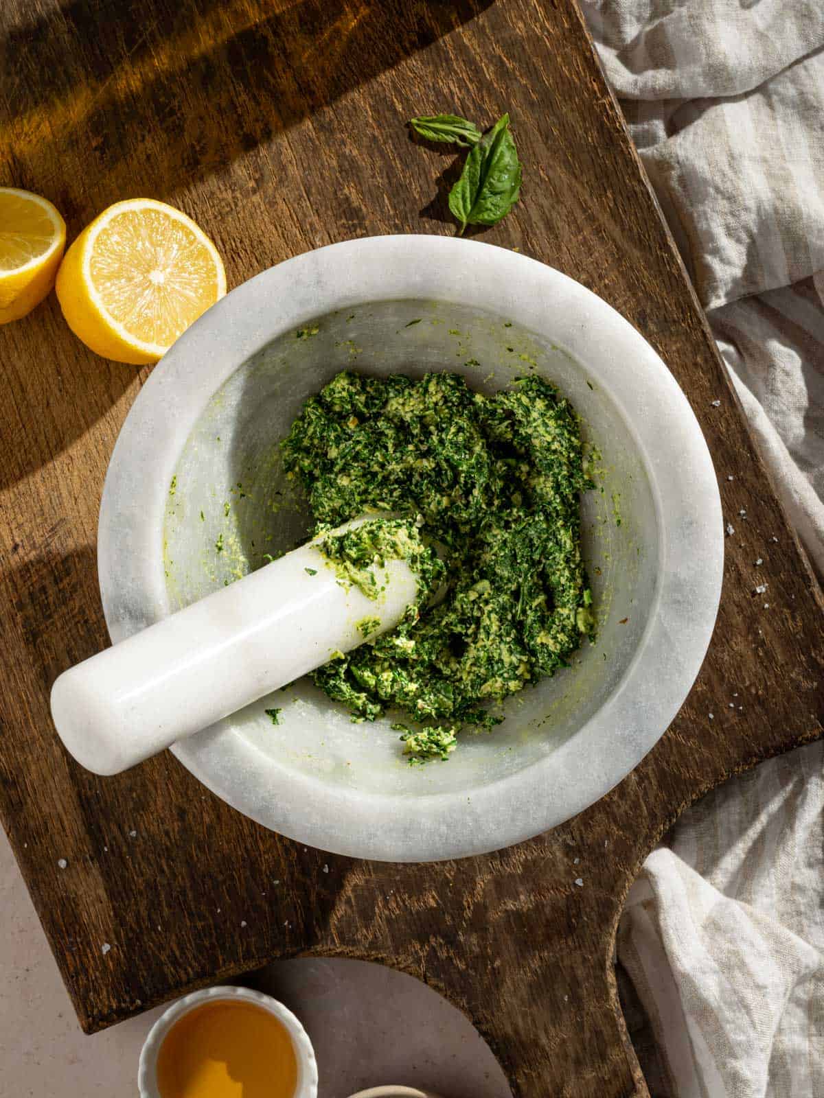 Mashed garlic, pine nuts, and basil in a large mortar.
