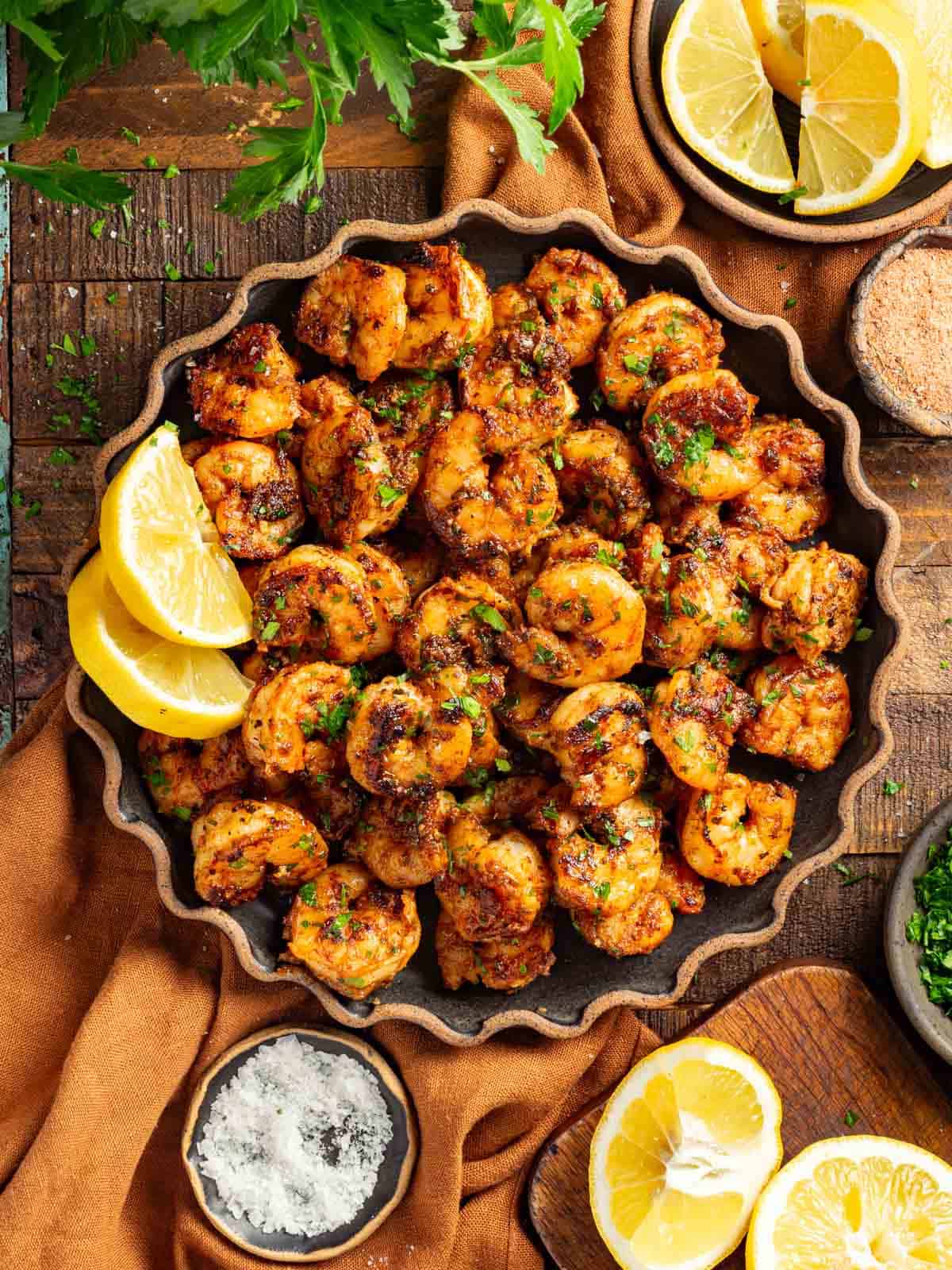 A plate of blackened shrimp topped with lemon and parsley
