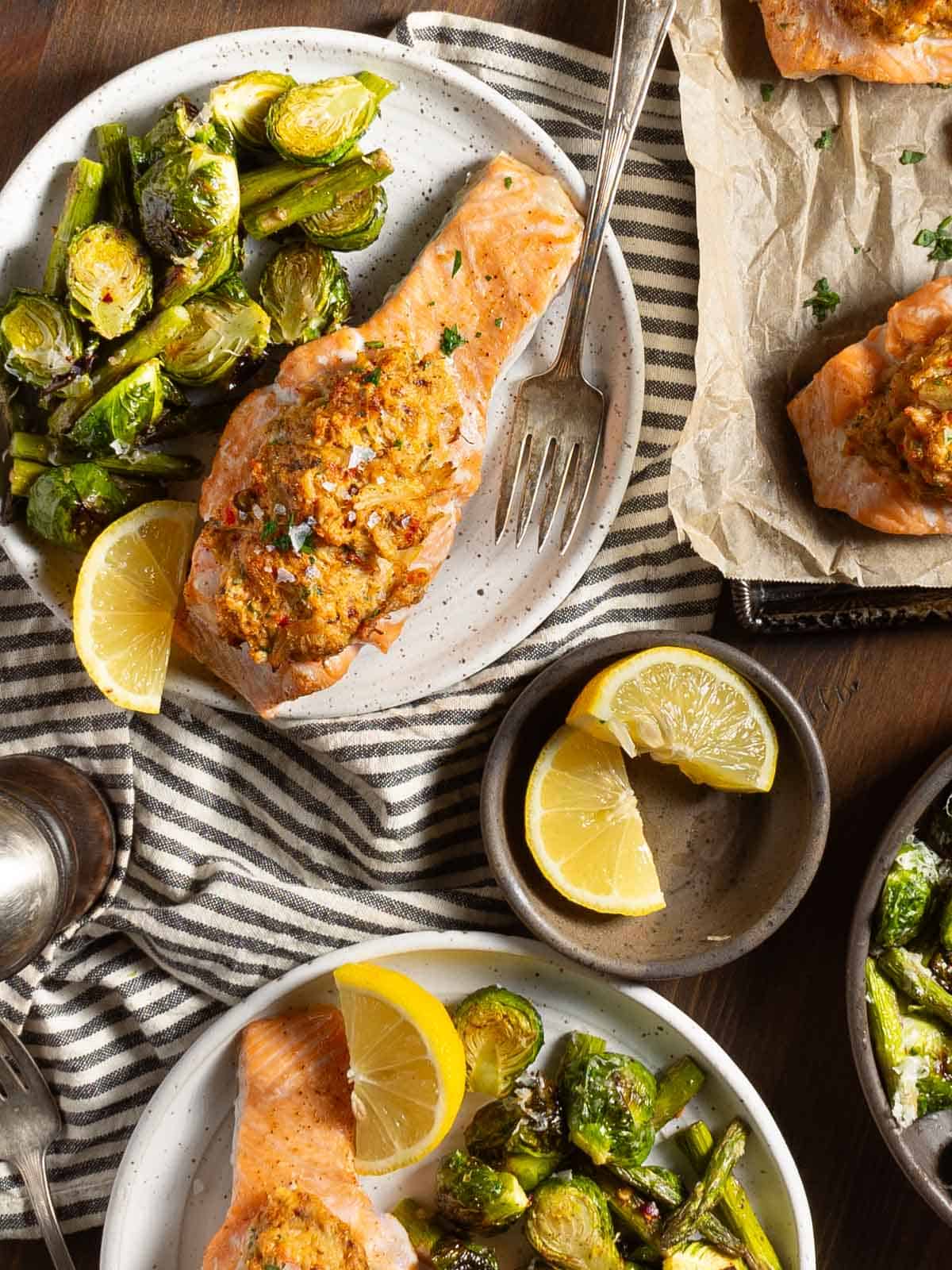 Cajun crab stuffed salmon on a plate with brussels sprouts and asparagus.