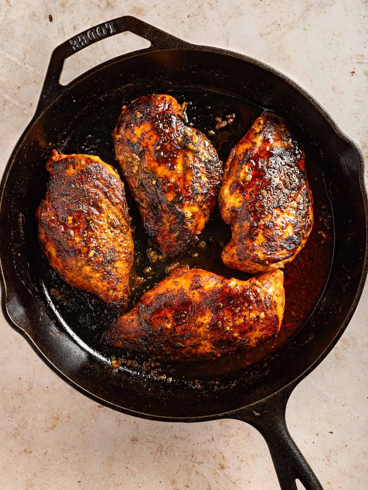 Seared blackened chicken breasts in a skillet.