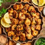 Up close plate of blackened shrimp with parsley and lemon.