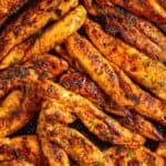 Up close blackened chicken tenders topped with parsley and garlic butter.