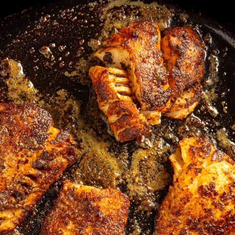 Blackened cod fillets in a cast iron skillet.