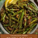 Cajun blackened green beans in a serving bowl with lemon wedges.