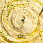 Up close creamy mashed potatoes with flakey salt, butter, and chives.