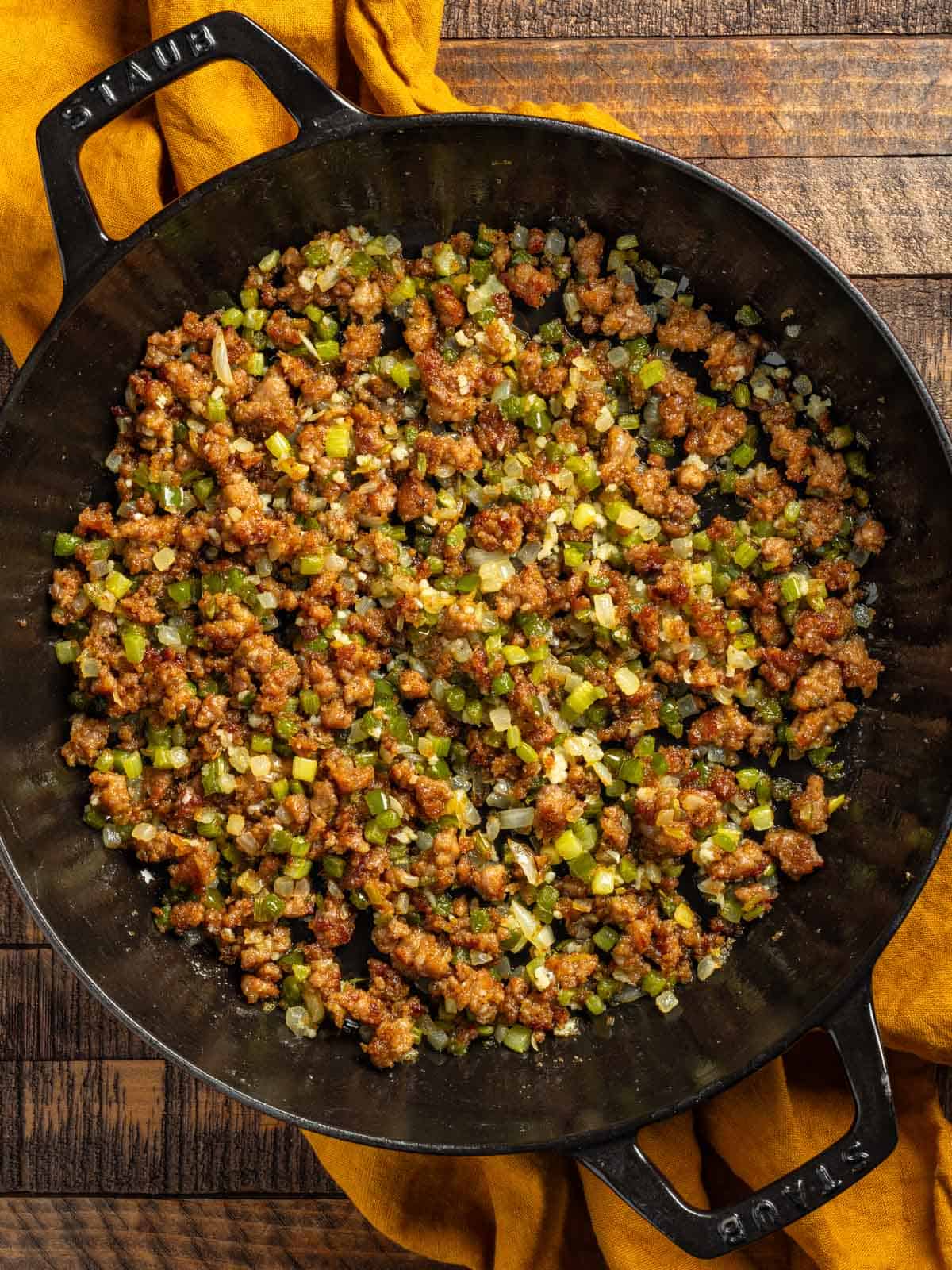 Sautéed holy trinity and sausage in a skillet.