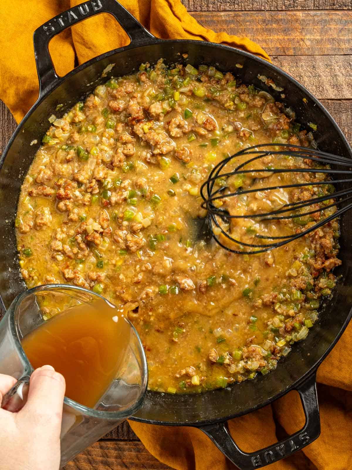 Whisking broth into a roux with onions, celery, and bell peppers.