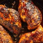 Blackened chicken breasts in a skillet with garlic butter.