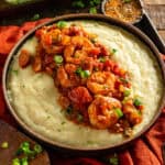 Cajun shrimp and grits in a bowl with green onions.