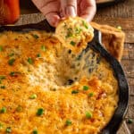 Dipping into creamy cajun crab dip with a cracker.
