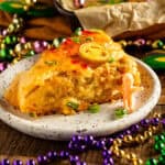 A cheesy boudin king cake slice on a plate with jalapeños and pepper jelly.