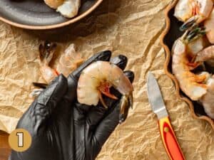 A shrimp in a gloved hand.